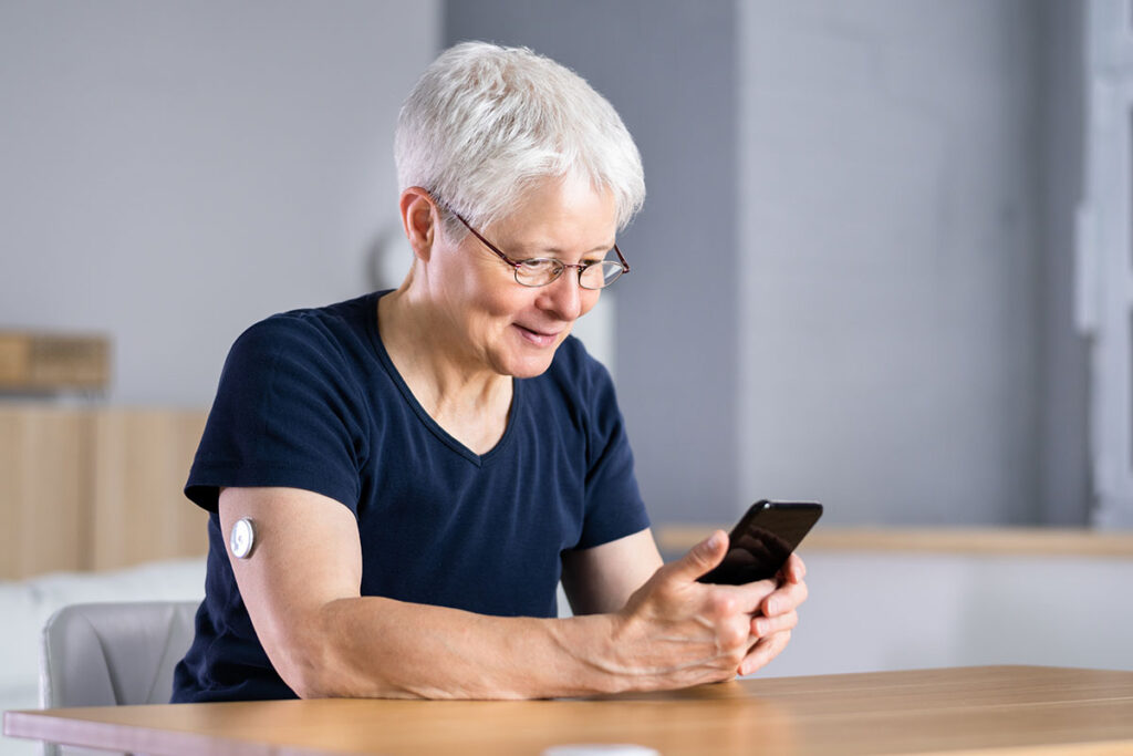 An older woman measures her blood sugar on a mobile device